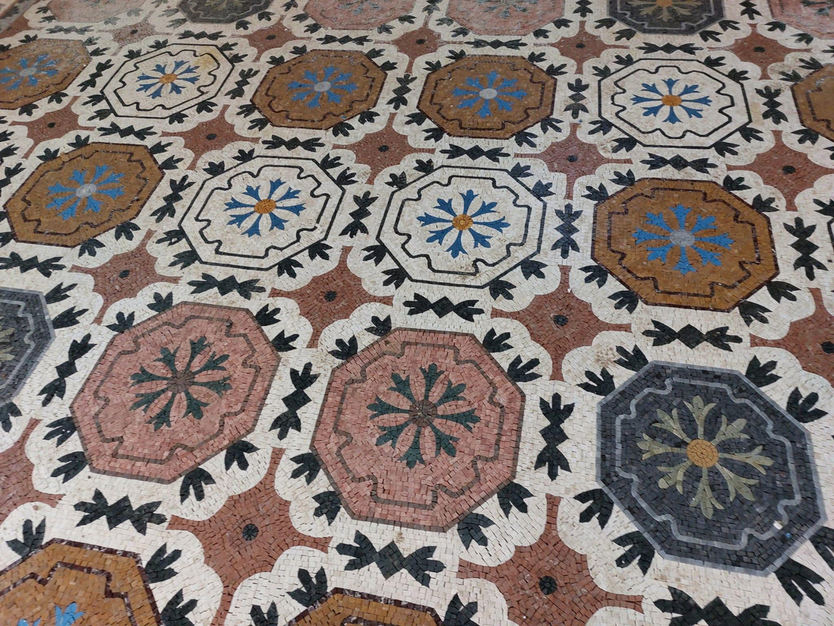 Detailed view of the classical Mediterranean vine scroll border on a satin-honed marble mosaic floor carpet.