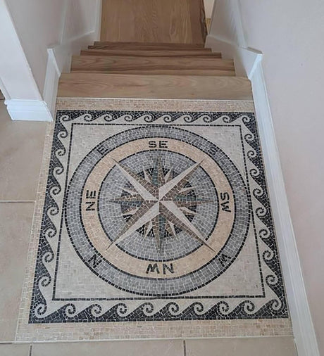 Residential staircase landing floor featuring a custom handcrafted nautical compass rose square marble mosaic medallion with a running wave border.