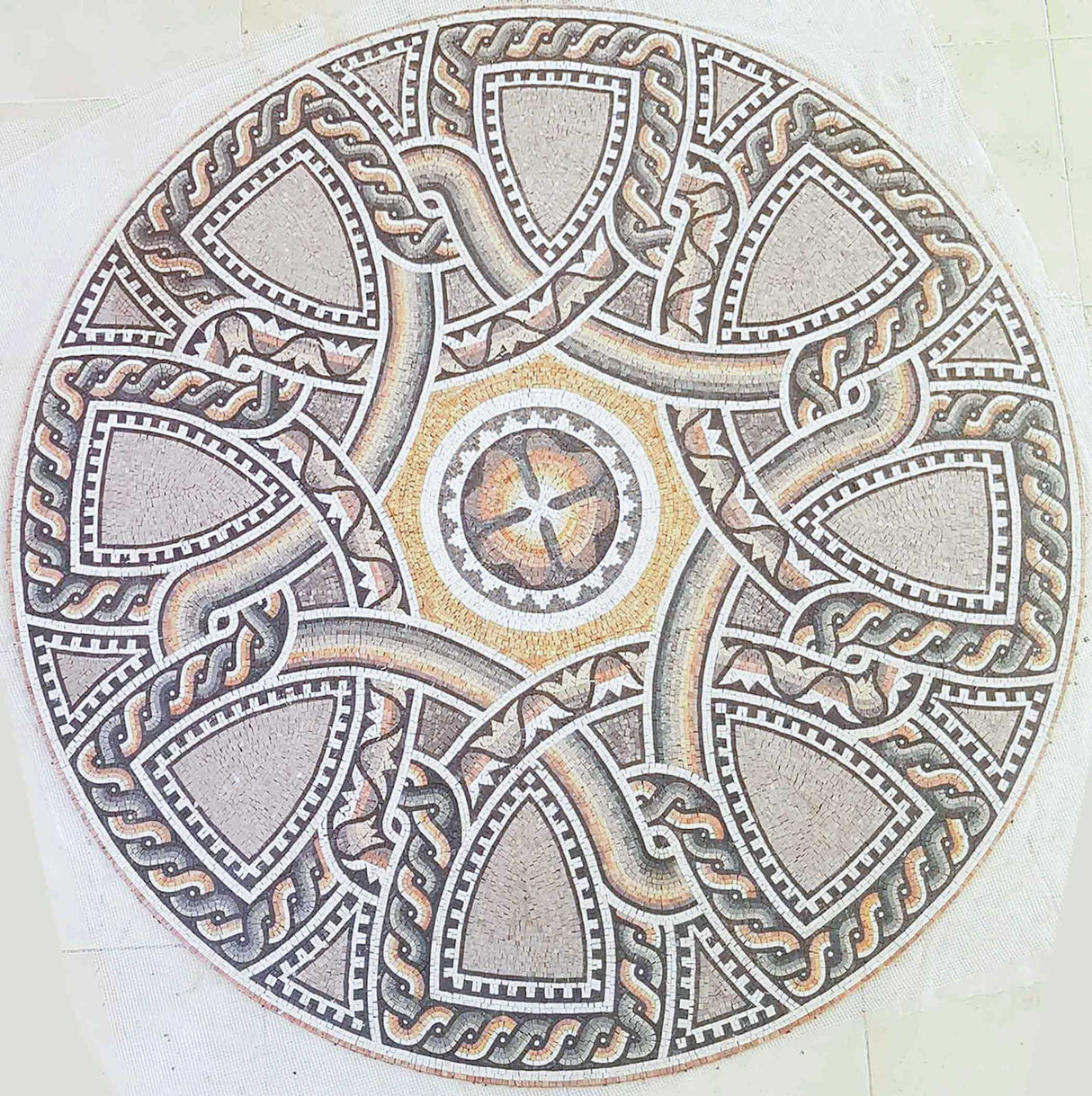 Top-down circular view of a classical Roman style geometric marble mosaic floor medallion featuring terracotta, yellow, and grey natural stones.