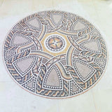 Perspective angle view of a hand-cut earth tone geometric marble mosaic medallion on mesh backing before installation.