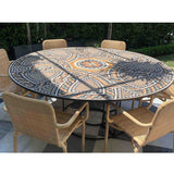 Custom round marble mosaic tabletop overlay with geometric interlocking patterns styled on an outdoor dining table with wicker chairs.